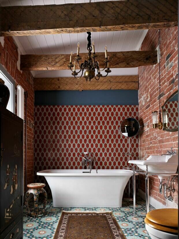 На двух стенах решили оставить текстуру исторической кирпичной кладки, очистив ее, а на пол и стену за ванной положили бетонную плитку ручной работы.