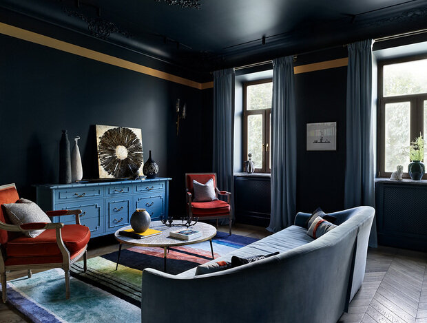 Красивые карнизы с декоративной лепниной выкрашены в цвет стен и потолка, поэтому узор выглядит очень деликатно. При этом дизайнеры добавили золотой кант по периметру стены, чуть ниже карниза, который сделал однотонные стены интереснее.