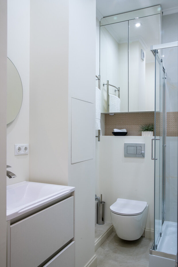 Зеркало в санузле расположено не только над раковиной, но и в отделке шкафчика над инсталляцией. 