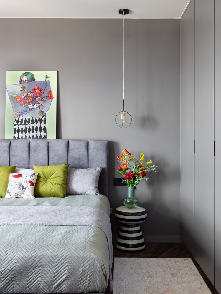В спальне выбраны более спокойные оттенки зеленого, которые перекликаются в текстиле, картине. Геометрии добавляет дизайнерский керамический пуф-столик.