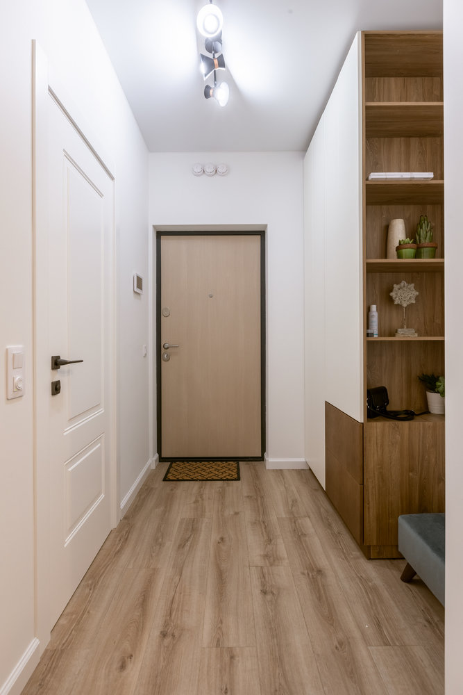 В прихожей есть вместительный шкаф для верхней одежды со встроенными в него открытыми полками, где расставили растения и предметы декора. Это создает ощущение уюта.