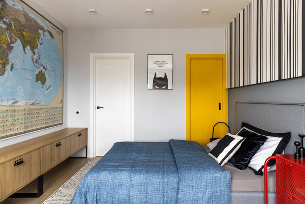 Карта мира напротив кровати вместо телевизора. Предусмотрели большой стол практически во всю стену и систему хранения для игрушек и книг. Желтая дверь задвигается в стену при открывании, за ней находится гардеробная комната.