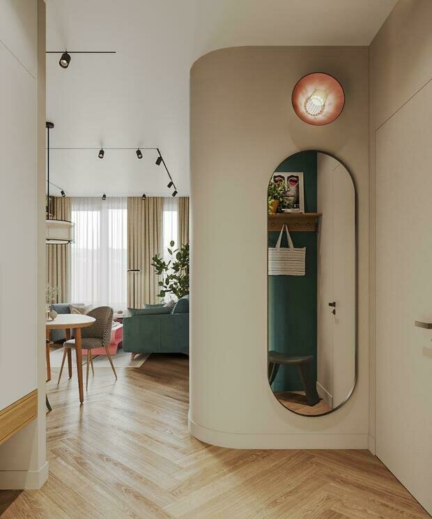 Плавный скругленный угол как бы приглашает пройти из функциональной прихожей в зону гостиной. Тема скругления поддерживается элементами в комнатах (журнальный столик, светильники, зеркало в прихожей и торшер).