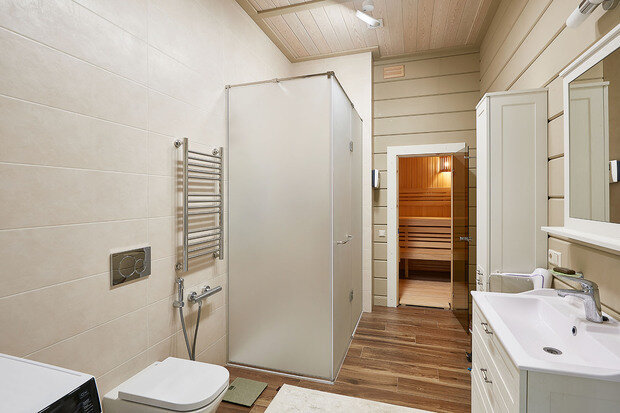 В ванной комнате первого этажа разместили небольшую семейную сауну площадью 3,8 кв. м. Для домашней сауны выбрали электрическую печь Harvia. Она совмещает в себе еще и парогенератор. В специальный отсек можно добавить аромамасла или сухие травы и наслаждаться лечебным паром.
