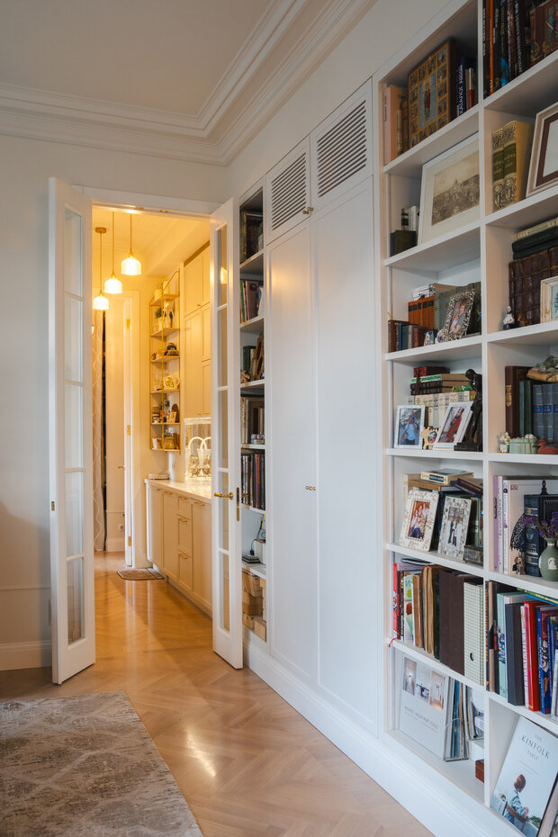 Интерьер гардеробной в классическом стиле с белыми стеллажами и книгами