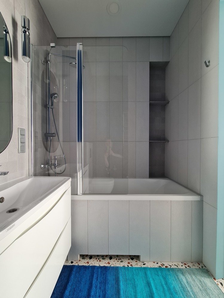 Натяжные потолки и виниловое покрытие позволили уложиться в заявленный бюджет и при этом не потерять в эстетике. Недорогая базовая плитка в большом санузле стала хорошим фоном для зеркала и яркой глянцевой стены.