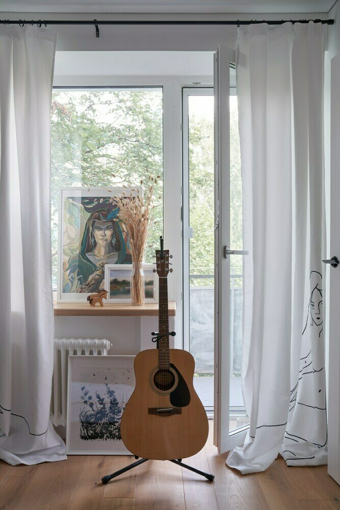 Радиаторы заменены на новые, но по форме напоминают старые чугунные. Двери с фаской и черными ручками — важный акцент. Такой же прием повторяется и в кухонном гарнитуре. Рисунок на шторах в гостиной перекликается с рисунком на фартуке — те же образы и графичность линий.