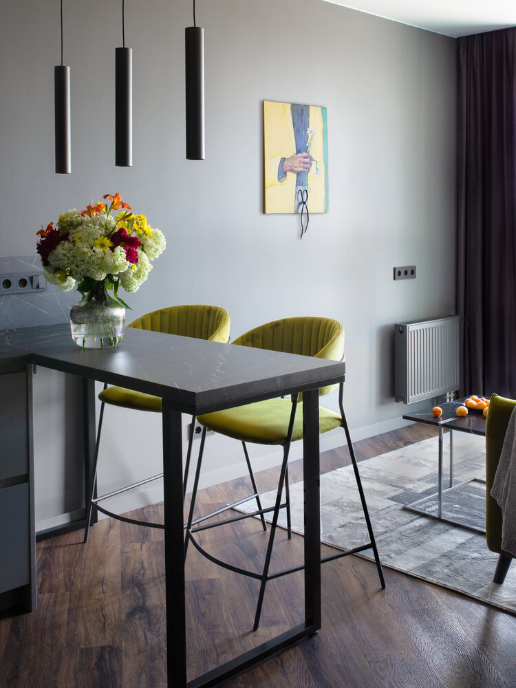 Темно-серый цвет стен служит холстом, где яркими пятнами выступает мебель — стулья и диван. И особенно сочно выглядят картины от художницы Натальи Липской. Они задают особое настроение и придают свой шарм всему интерьеру.