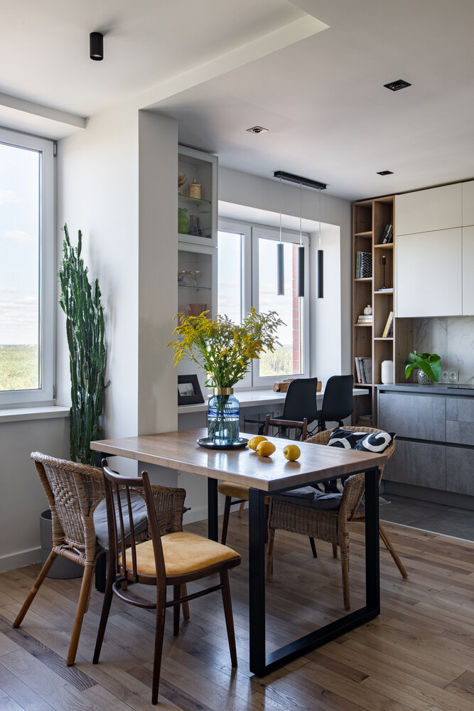 В обеденной зоне дизайнер предусмотрела подвесные прозрачные витрины, в которых хранятся винтажные хрустальные вазы и бокалы. Для изготовления стола выбрали деревянный щит с понравившимся рисунком, купили металлическое подстолье и скрепили эти элементы, что позволило сэкономить на обеденном столе, при этом не потерять в качестве и самим поучаствовать в изготовлении индивидуального предмета мебели.