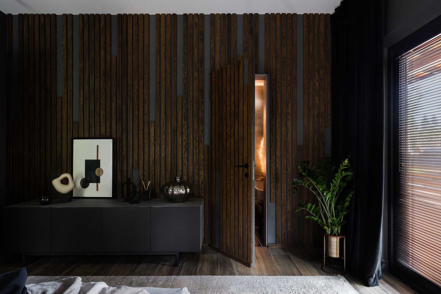 Стена напротив кровати оформлена деревянными рейками, дверь потайная.