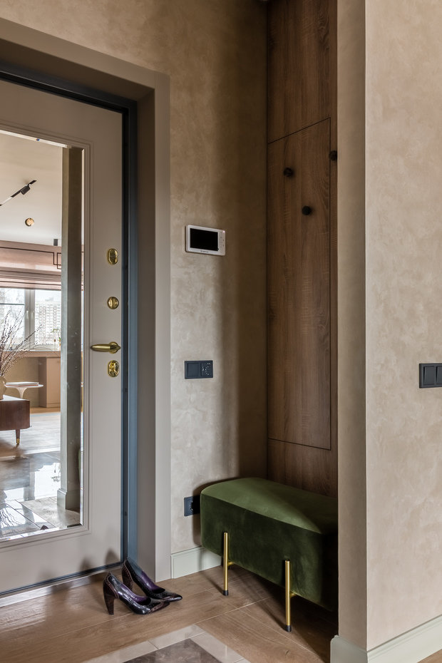 Стена прихожей с секретом. За стеновыми панелями спрятана дверь скрытого монтажа, ведущая в санузел и встроенный шкаф. Эти приемы работают на создание чистого, «не заставленного» пространства.