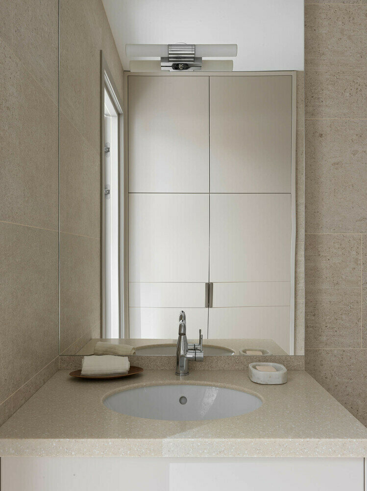 В гостевом санузле выделили нишу, в которой сделали зону для стиральной и сушильной машины, а также для хранения различных бытовых предметов и бытовой химии. Также здесь организовали большую зону душевой, удобную тумбу для раковины и зеркало.