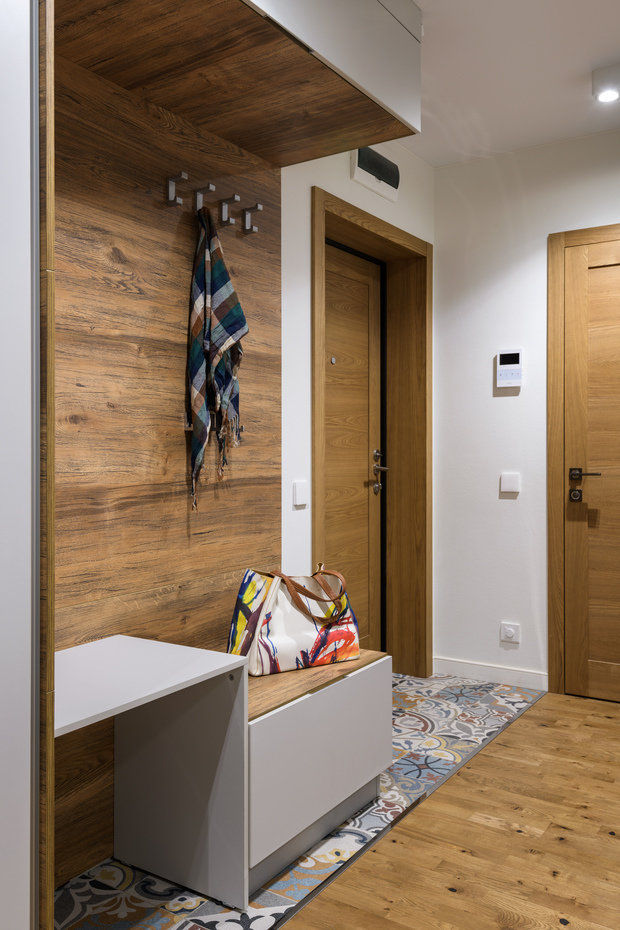 Входная зона в прихожей выполнена по эскизам дизайнера. В ней размещены высокая зона-столик для высокой обуви и низкая тумба-скамья для повседневной обуви.