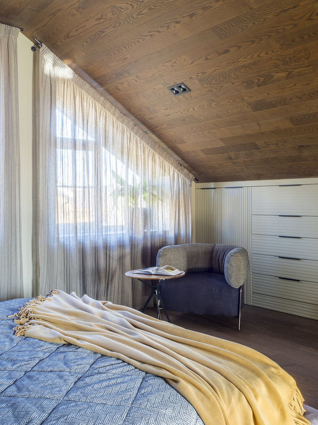 Хранение в спальне размещено в шкафах и комодах, встроенных вдоль скошенной стены.