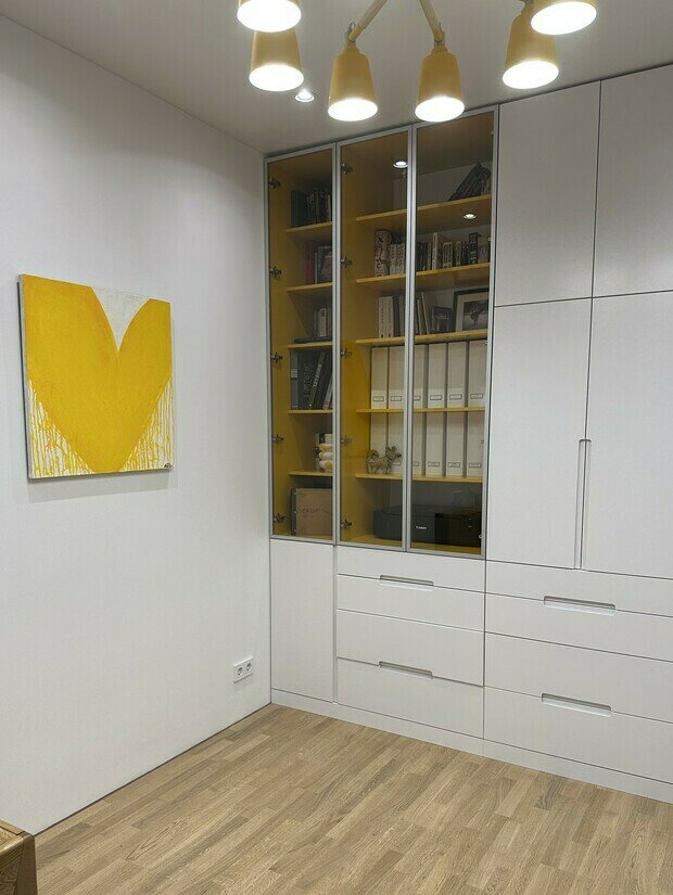Интерьер гардеробной в современном стиле с белым шкафом и желтыми полками