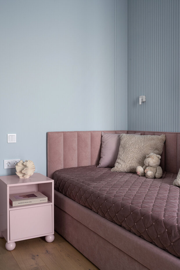 Интерьер детской в современном стиле с розовой кроватью и прикроватной тумбой