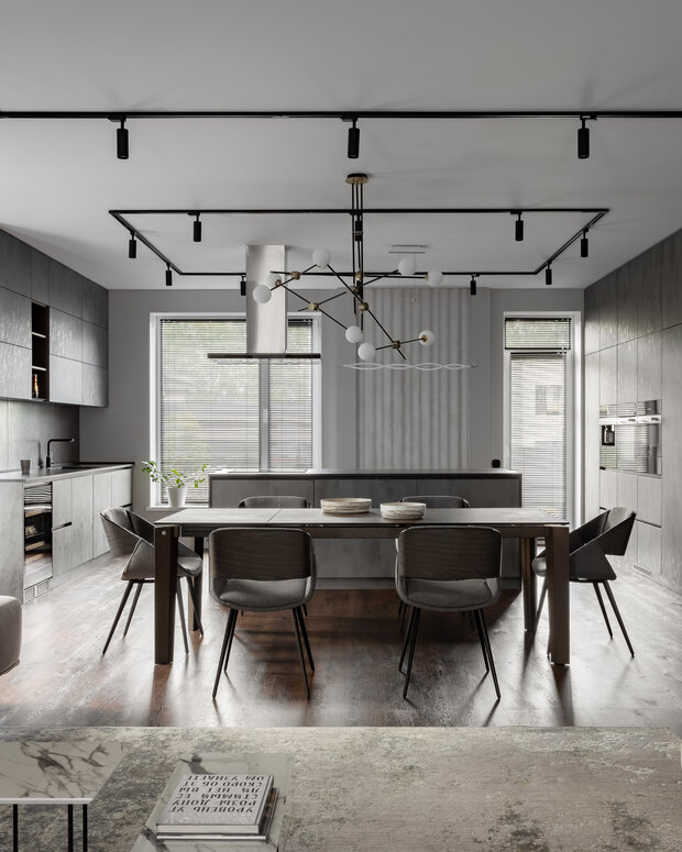 Кухня выполнена на заказ, вся техника встроена, фасады под бетон. Фартук — керамогранит, но имитирует железные листы.