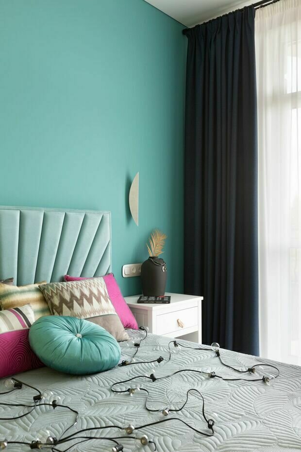 Интерьер спальни в современном стиле с бирюзовыми стенами и декоративными подушками