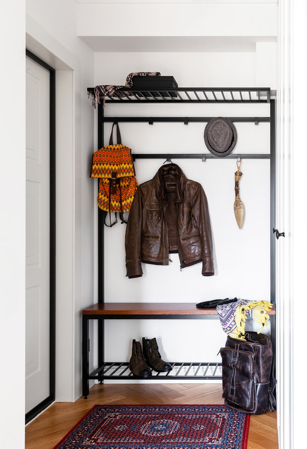 В прихожей в ходе перепланировки создали нишу, в которую интегрировали вместительный встроенный гардеробный шкаф. Для повседневной одежды и аксессуаров рядом с дверью по чертежам дизайнеров выполнили открытую вешалку с крючками и полками.