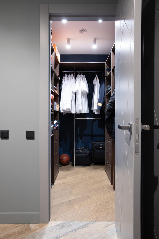 При входе в квартиру организовали гардеробную комнату, довольно вместительную, здесь же сделали отделение для гладильной доски.