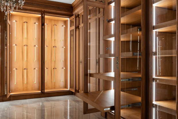Интерьер гардеробной в классическом стиле с деревянными шкафами и подсветкой