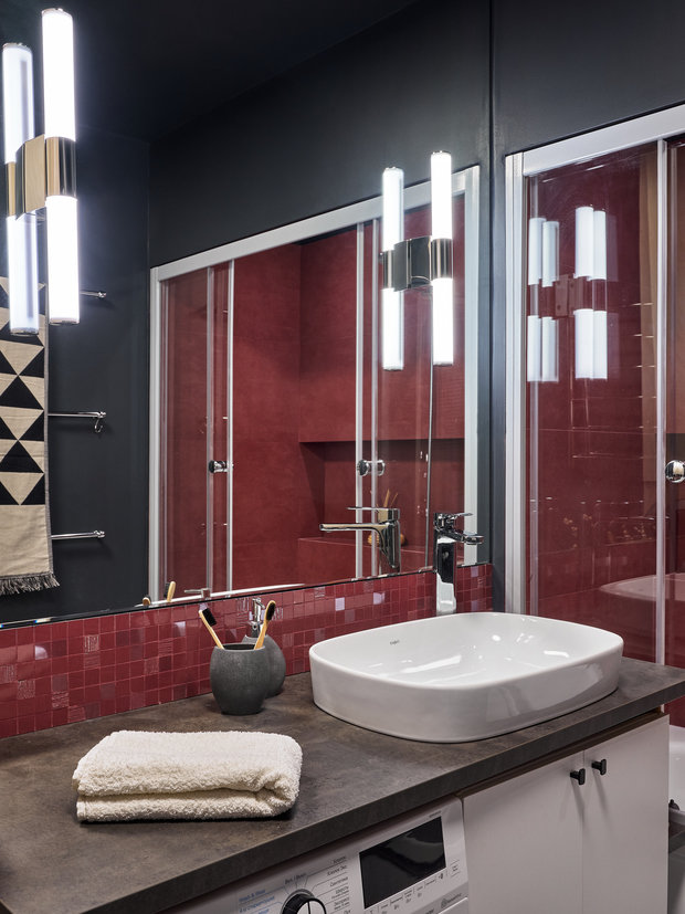 Инсталляция обшита ГВЛ и фанерой, над ней продумано хранение бытовых предметов, а со стороны умывальника расположены закрытые полки для косметики.